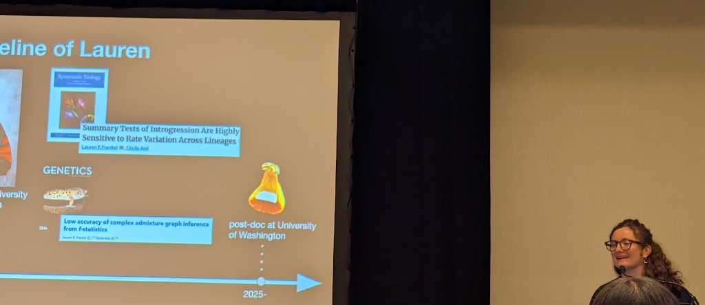 A young scientist, wearing glasses, stands at a podium next to a powerpoint presentation. The slide is half-visible, showing screenshots of published papers and the text 'post-doc at University of Washington'